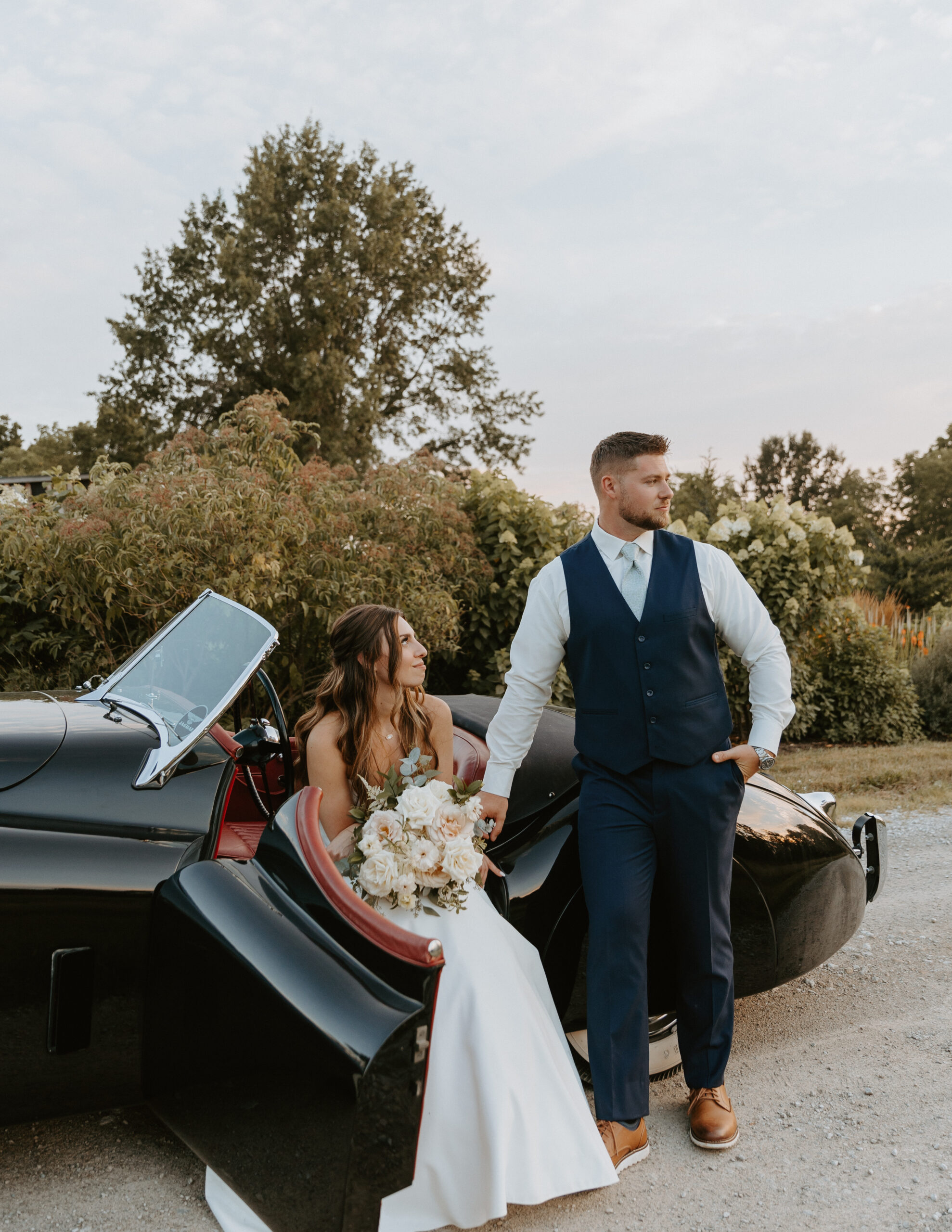 Modern bride and groom portraits with a classic vintage getaway car