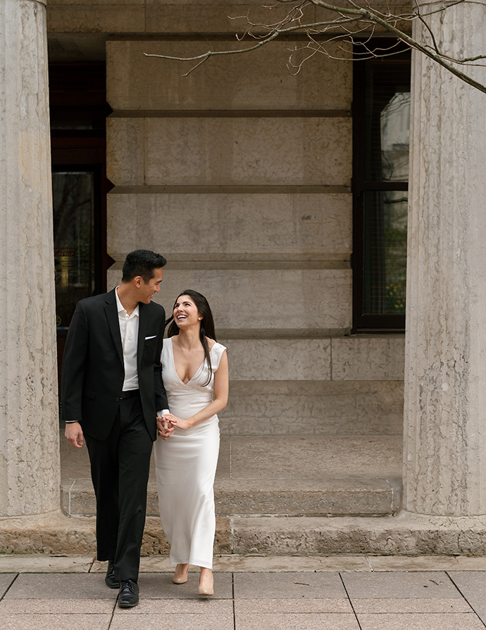 A bride and groom stroll together down the street in front of the Columbus Ohio Statehouse.