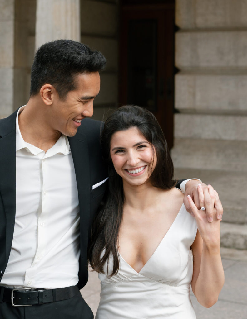 A smiling couple in wedding attire gazes at each other in front of the Columbus Ohio Statehouse.