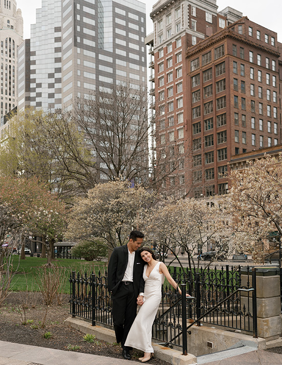 The bride and groom pose happily in front of a cityscape, capturing their special moment. Photography by Stevie Davis.