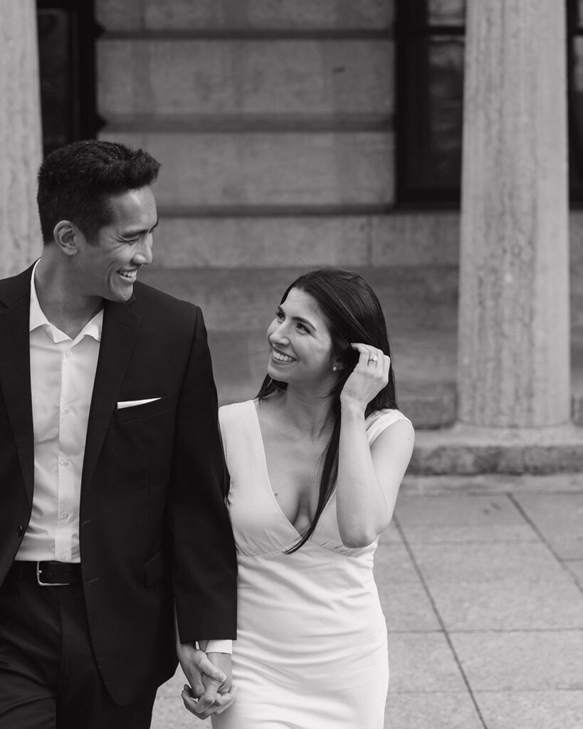 A black and white photo of a couple walking together in front of the Columbus Ohio Statehouse.