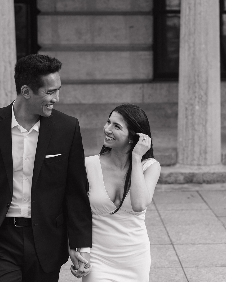 A black and white photo of a couple walking together in front of the Columbus Ohio Statehouse.