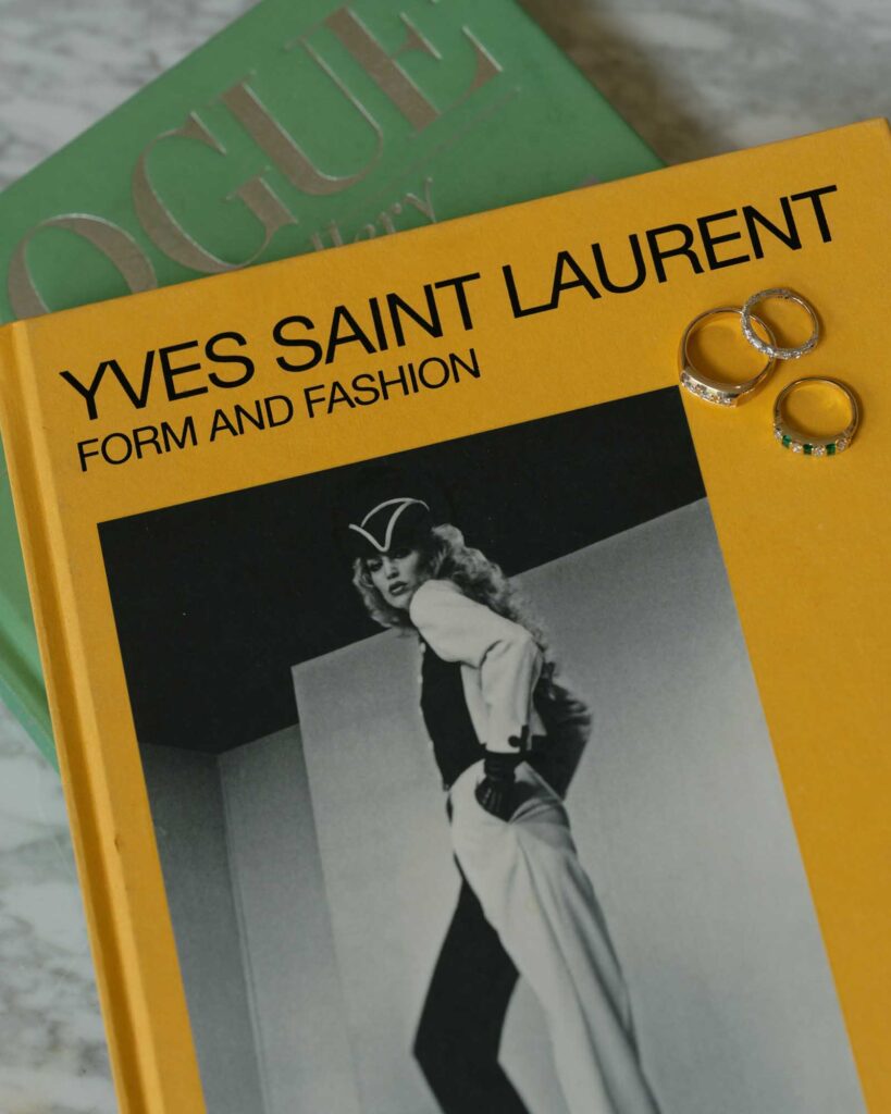 Yellow book titled "Yves Saint Laurent: Form and Fashion" with a black-and-white photo of a model. Three rings are placed on the book.