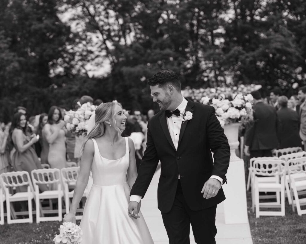 Franklin, Ohio bride and groom walk down the aisle, hand in hand, surrounded by smiling guests. The scene conveys happiness and celebration.