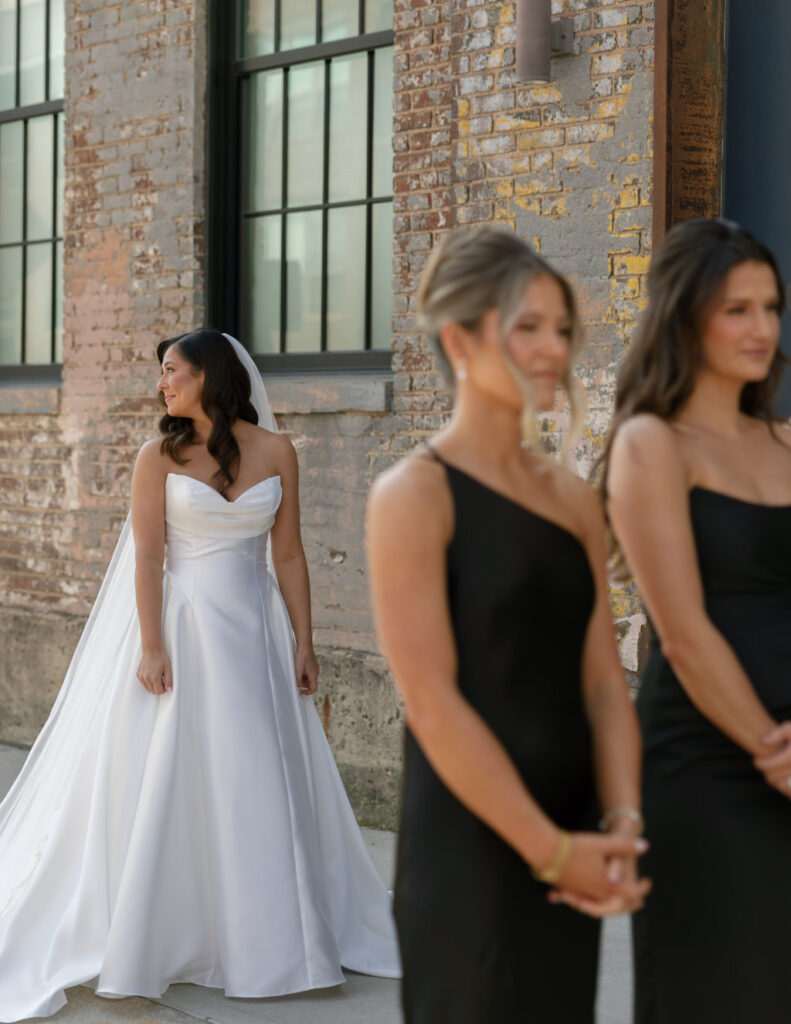 Bridesmaids reacting emotionally during the bride’s first look in a bright indoor prep space.
