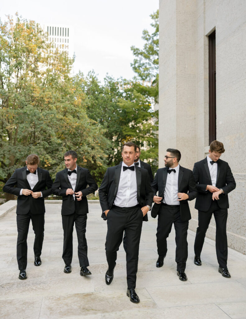 The Walkers’ groomsmen lined up outdoors in downtown Columbus in classic black suits.