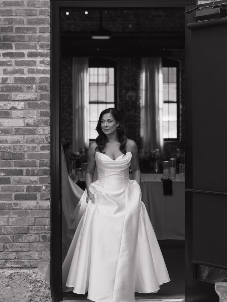 Black-and-white portrait of the bride entering through a doorway at The Ellis, captured on film by Stevie J Davis Photography.