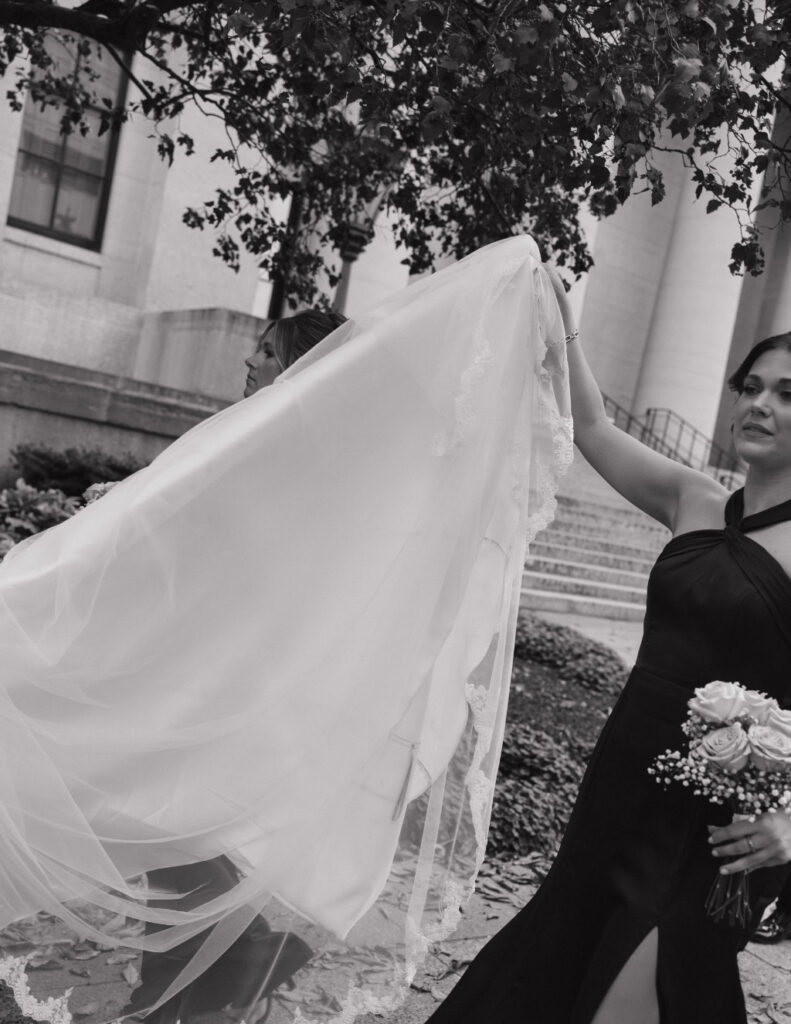Bridesmaid holding up brides wedding gown in downtown Columbus before the ceremony.