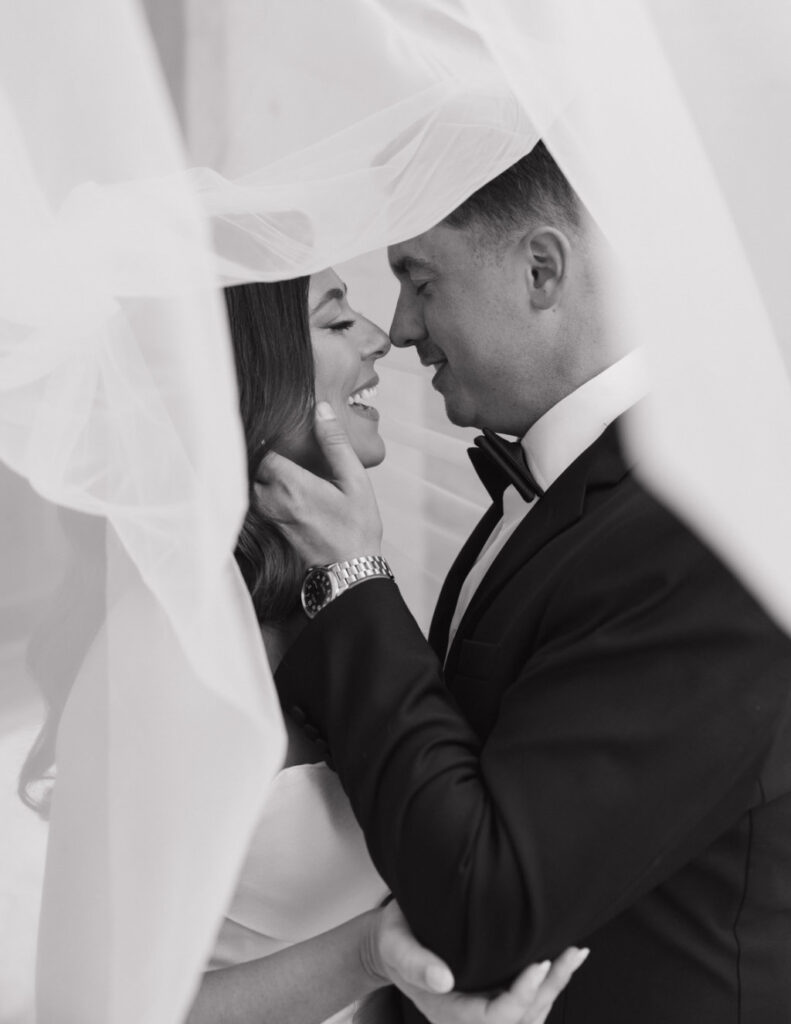 Black-and-white film image of the bride and groom kissing.