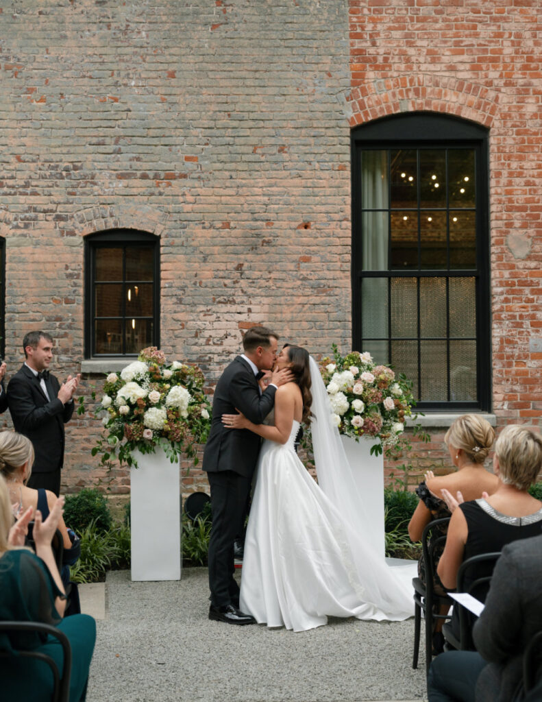 Industrial-style ceremony setup at The Ellis featuring tall brick walls and a polished aisle.
