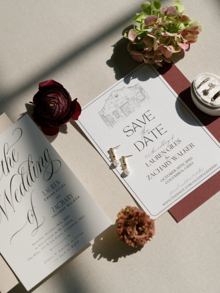 Elegant stationery suite displayed on a fabric backdrop with florals.