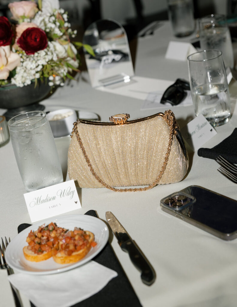 Bridal clutch, lipstick, and jewelry arranged neatly on the table.