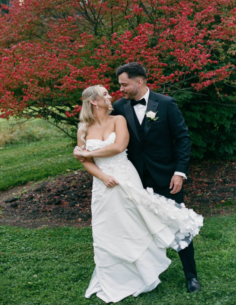 Bride and groom walking hand in hand across the lawn at The Everhart Gathering Place.