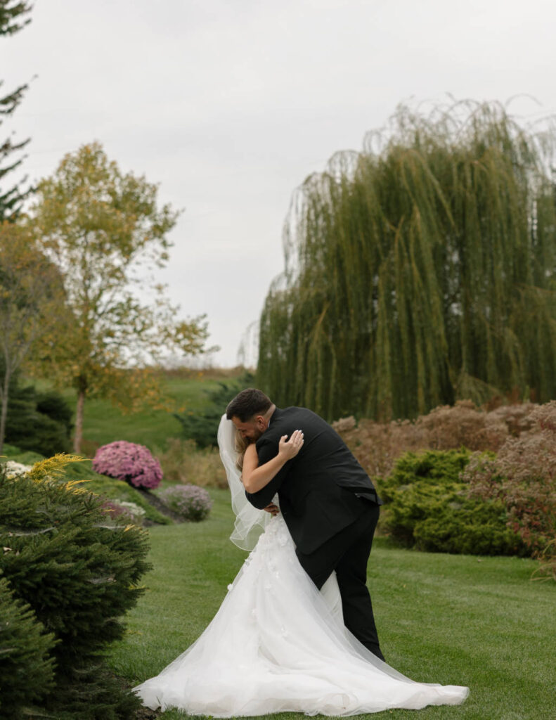 Bride in her wedding gown embracing her husband outside the venue in Wyandot County, Ohio.