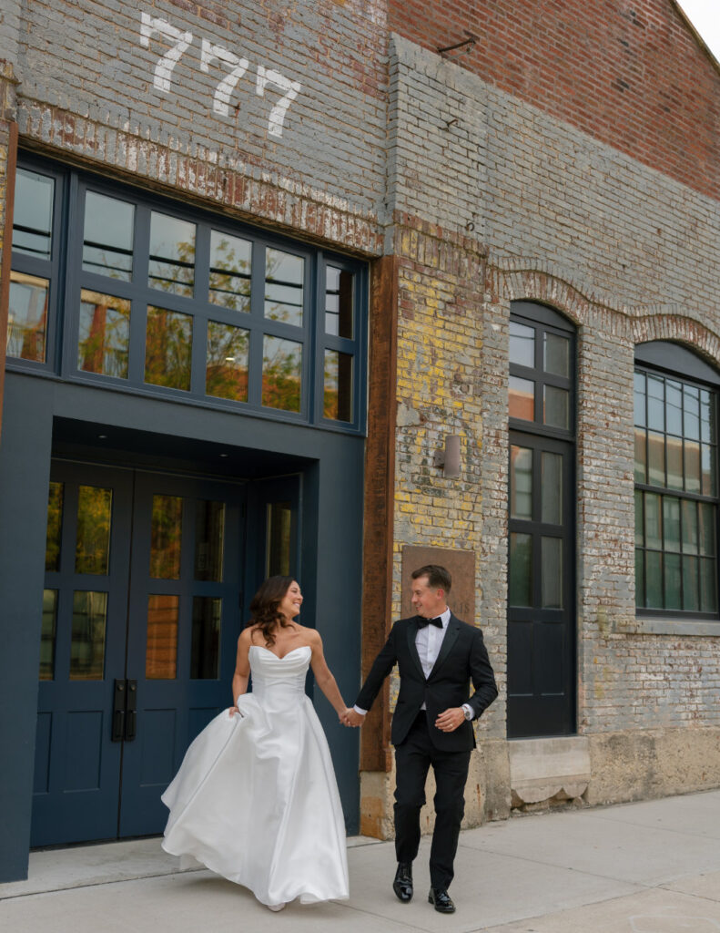 The couple walking together outside The Ellis surrounded by downtown architecture.