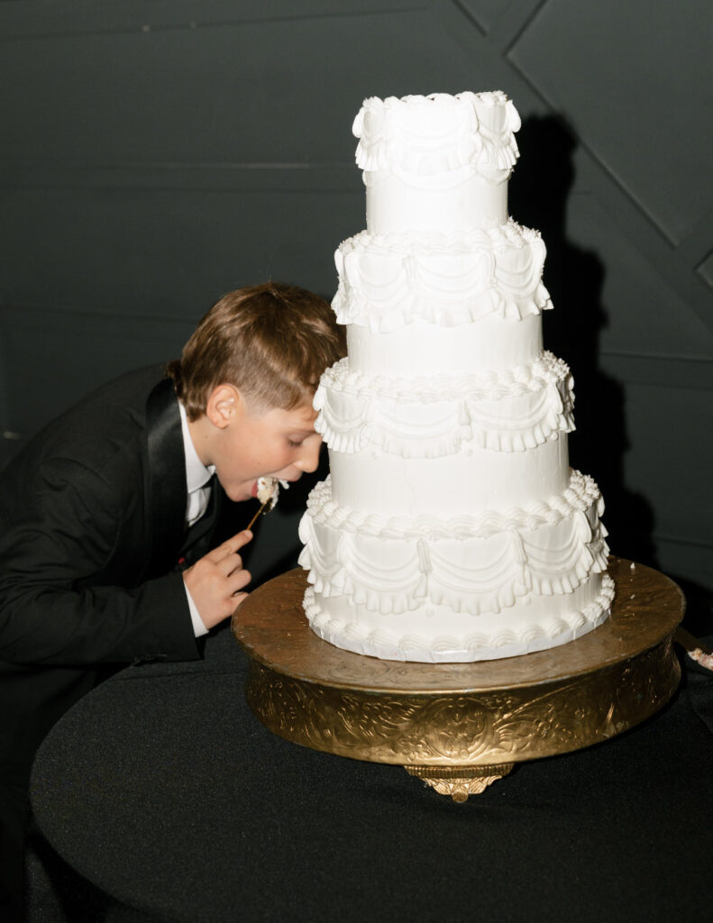 Four-tier white wedding cake displayed at The Ellis reception.