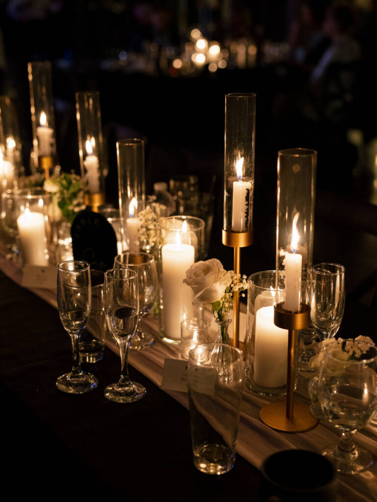 Luxurious tablescape featuring candles, greenery, and warm lighting.